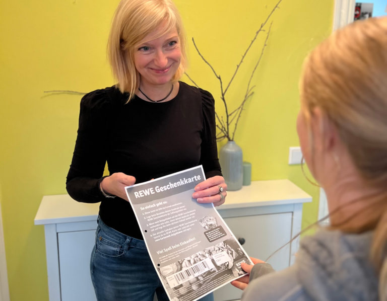 REWE-Gutscheinübergabe von einer Frau zu einer anderen